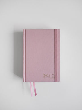 Pastel blush pink B6 2026 vertical planner featuring simple typography and matching decorative ribbon accents for comprehensive yearly planning.