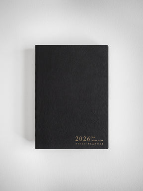 Sleek black B6 daily planner featuring elegant gold lettering that displays the year 2026 and "Full Year Daily Planner."