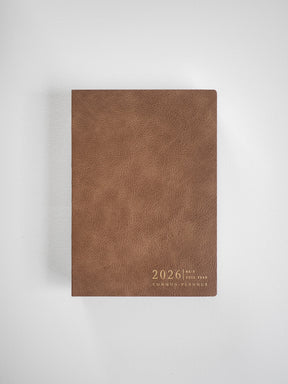 Minimalist B6 vertical planner cover in warm brown, featuring a textured, leather-like finish and elegant debossed text displaying "2026 Common Planner."