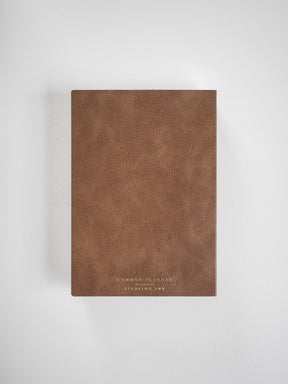 Elegant B6 vertical planner with a rich, matte brown textured cover, featuring subtle embossed gold lettering identifying it as the 2026 Common Planner.