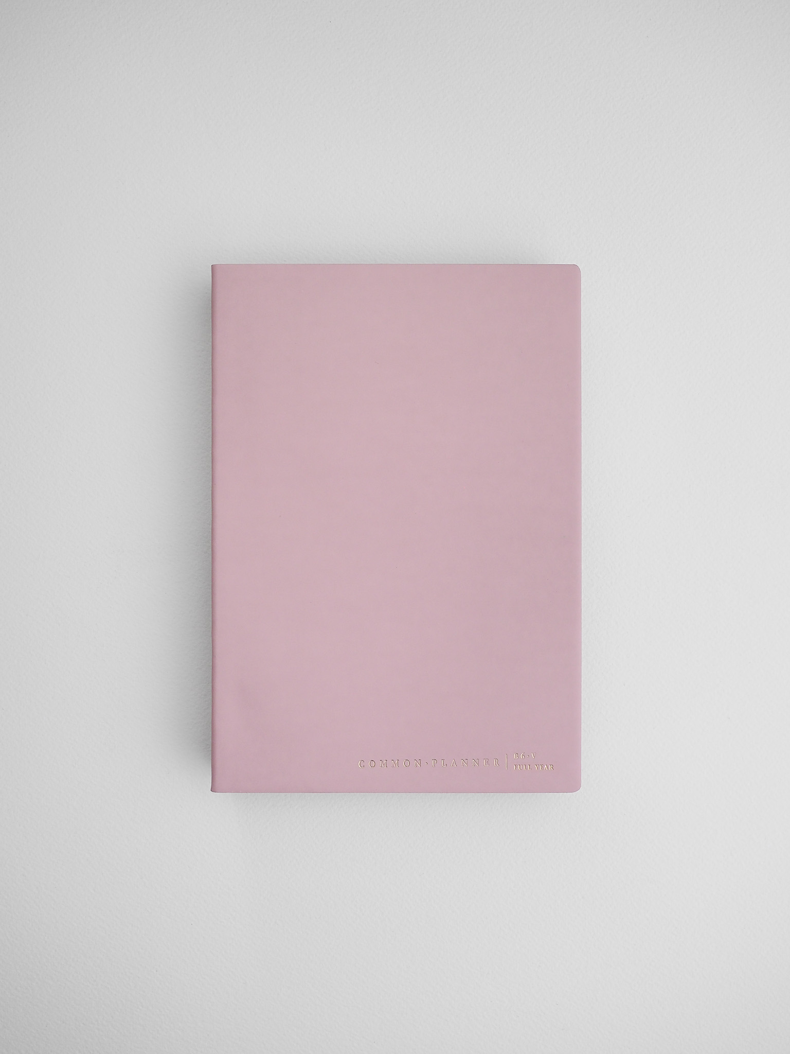 Minimalist blush pink planner notebook featuring a solid cover and "Common Planner London" branding, ideal for year-at-a-glance planning.