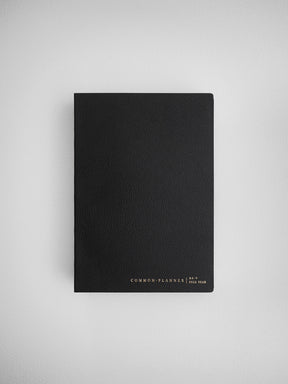 Minimalist black B6 vertical planner cover featuring subtle white lettering that reads "COMMON PLANNER | B6 V FULL YEAR."