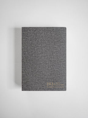 Textured dark gray vertical planner featuring elegant gold foil embossing of the year 2026 on the cover.