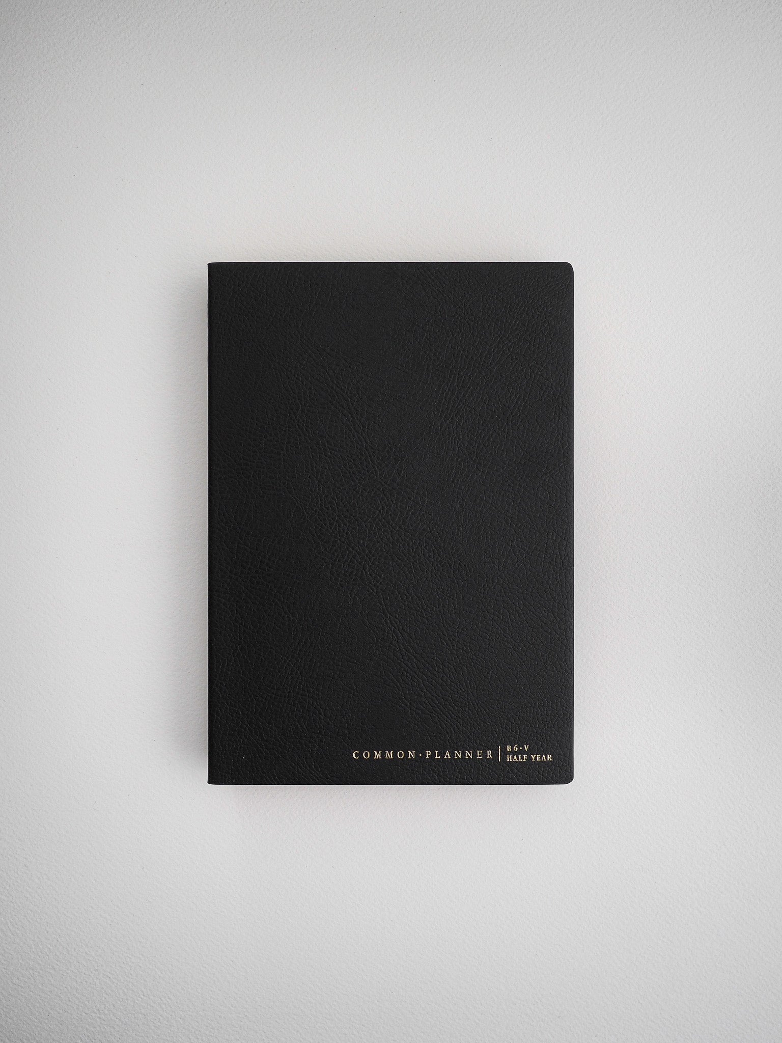 Minimalist black B6 common planner cover for half year scheduling, featuring elegant centered branding for an organized aesthetic.