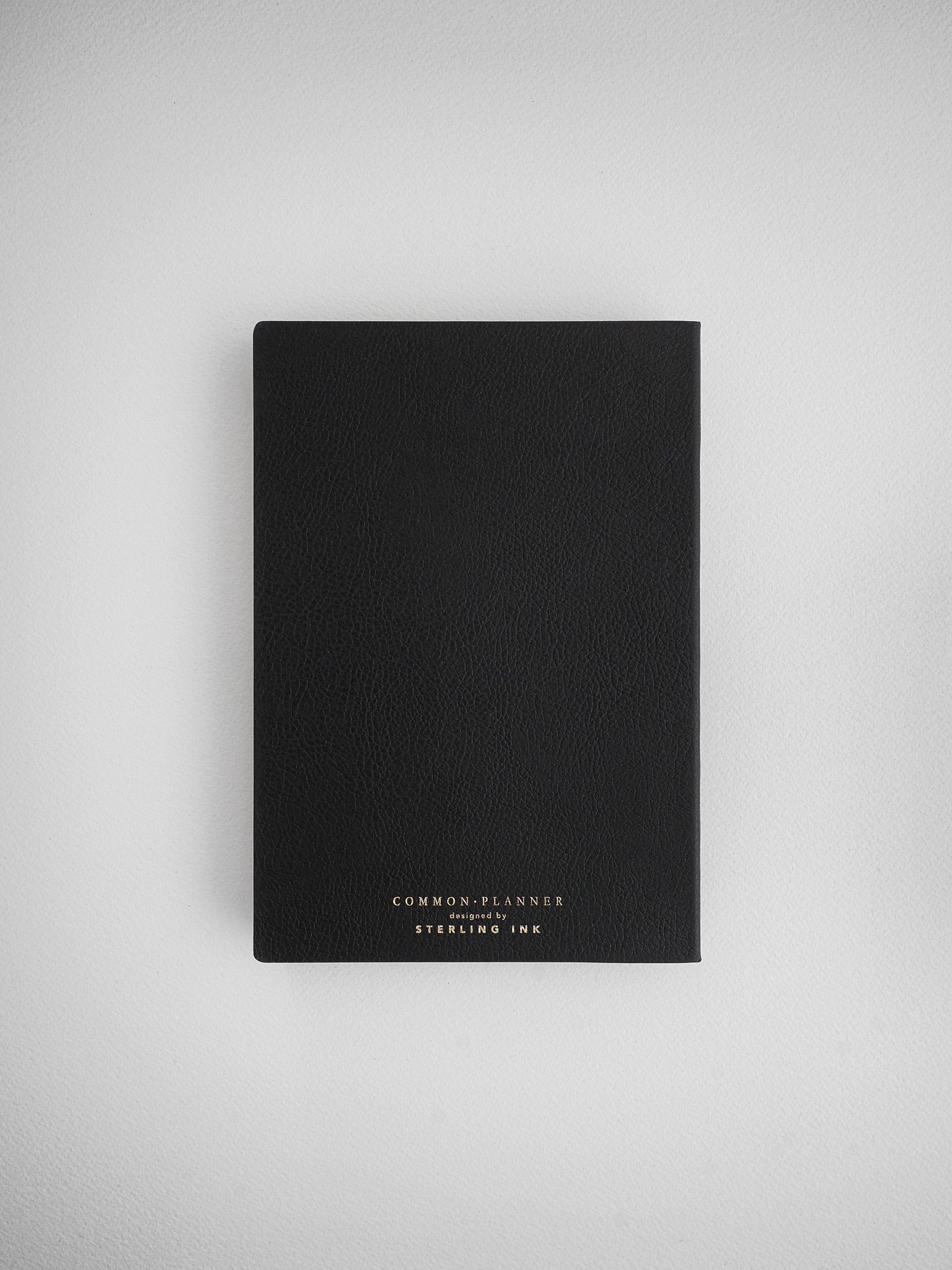 Minimalist solid black planner notebook for undated planning, featuring light text branding reading 'Common Planner' designed by Sterling Ink.