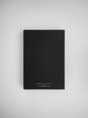 Minimalist solid black planner notebook for undated planning, featuring light text branding reading 'Common Planner' designed by Sterling Ink.