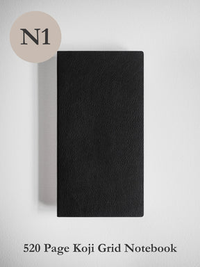 A black textured notebook with a grid layout, shown closed against a light gray background. A beige circle in the top-left corner displays the text 'N1', and the bottom text reads '520 Page Koji Grid Notebook'.
#Color_Onyx