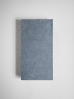Elegant compact planner with a textured, dusty blue-gray cover and subtle embossed branding near the bottom.