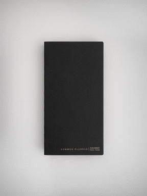 Minimalist black compact planner with a matte, structured cover, featuring "Common Planner" branding and designed for comprehensive full year organization.