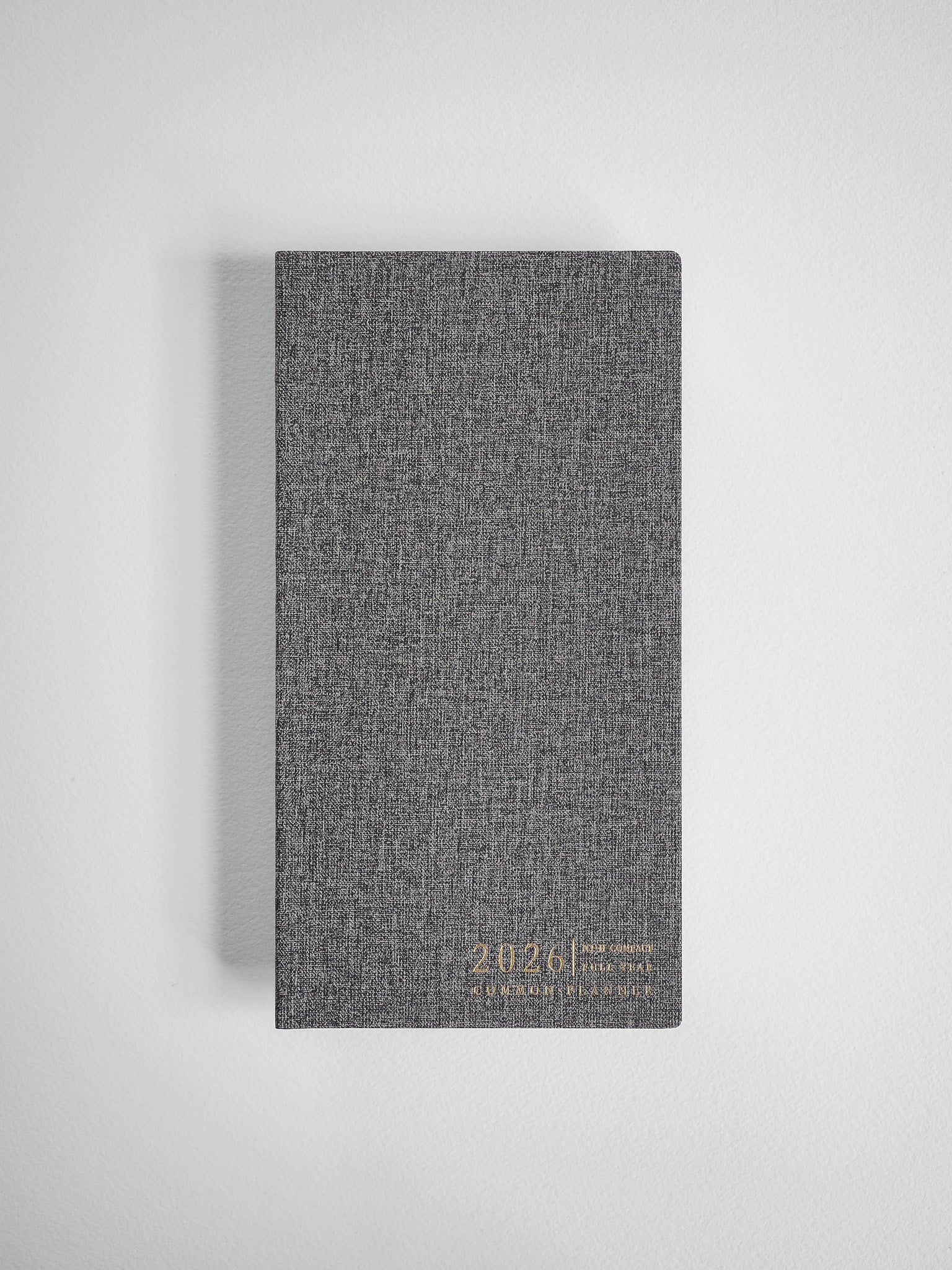 Dark charcoal gray planner with a heathered, textured finish and embossed commemorative text for the 2026 Common Planner.