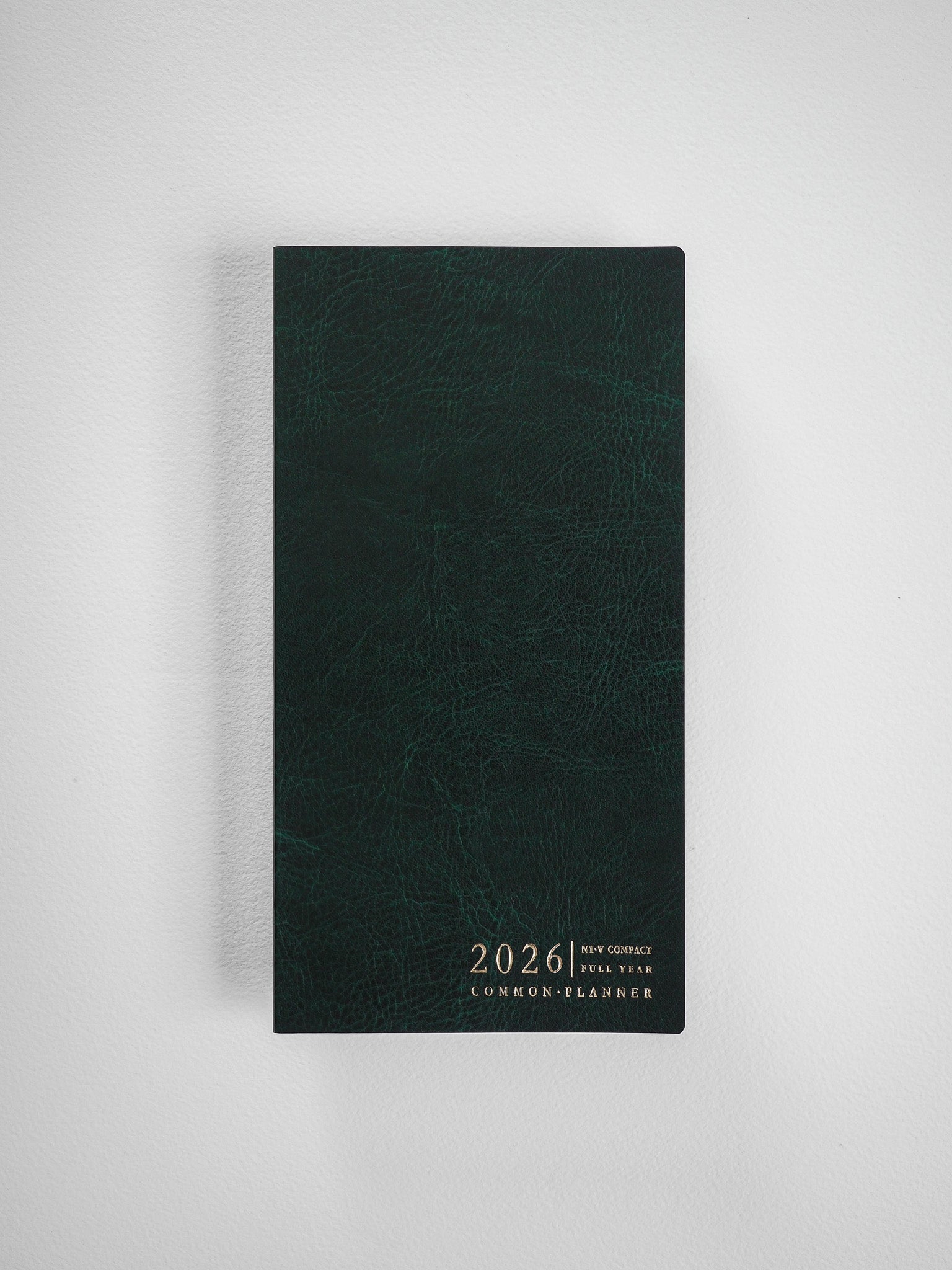 Dark forest green compact planner featuring debossed text reading "2026 N1 V COMPACT FULL YEAR COMMON PLANNER" centered on the cover.