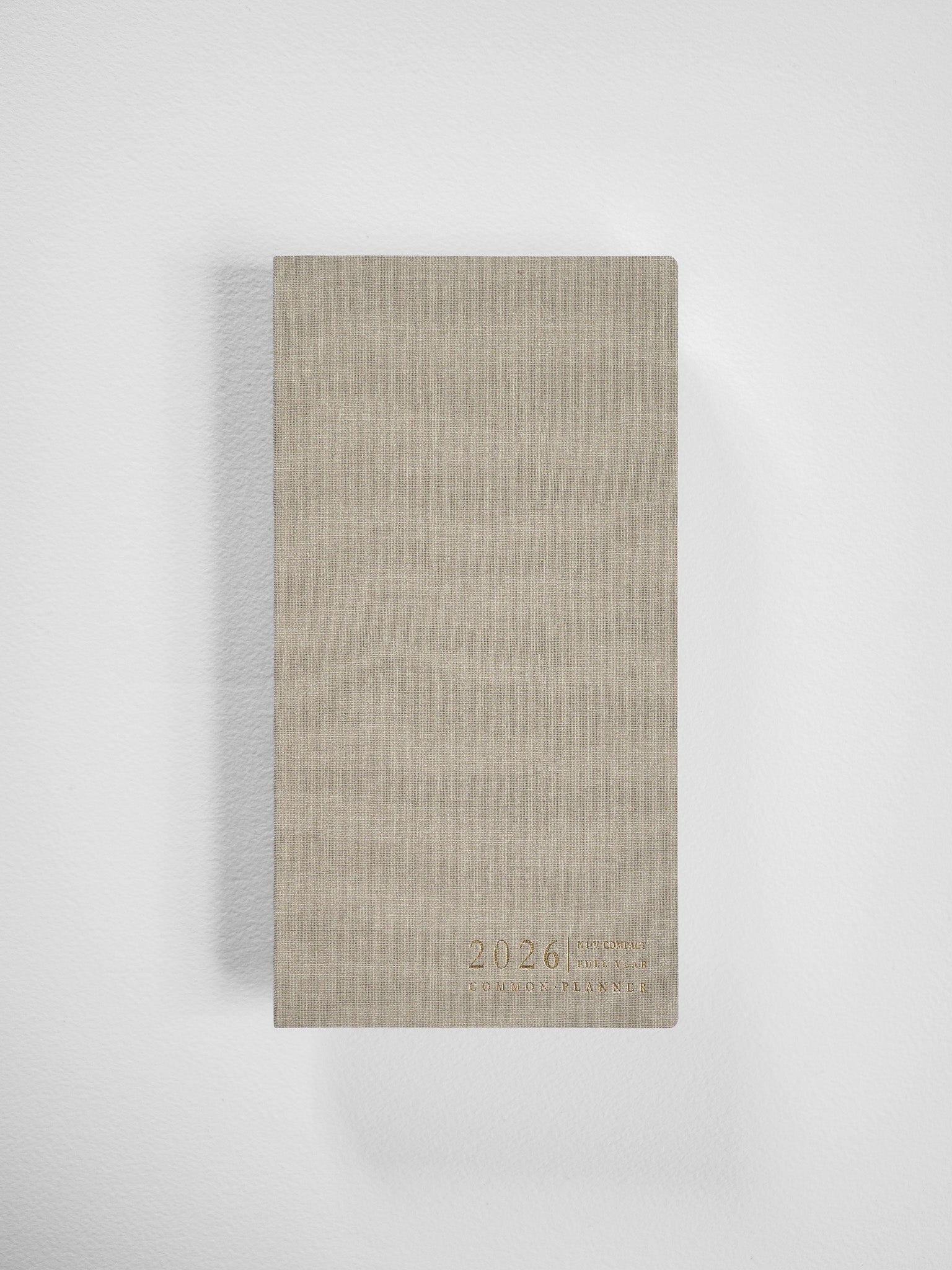 Minimalist 2026 planner featuring a vertical, neutral beige cover with centered, clean typography that identifies it as the Common Planner.