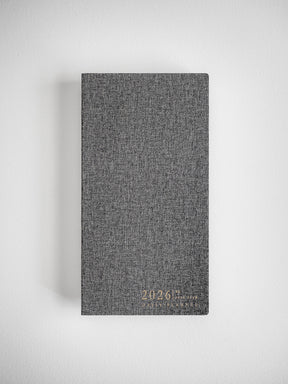Deep charcoal gray planner with a textured linen cover, subtly embossed with the year 2026, ready for daily scheduling.