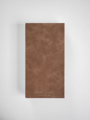Vertical planner with a deep, textured brown faux leather cover, elegantly embossed with "Common Planner" in subtle gold foil lettering.