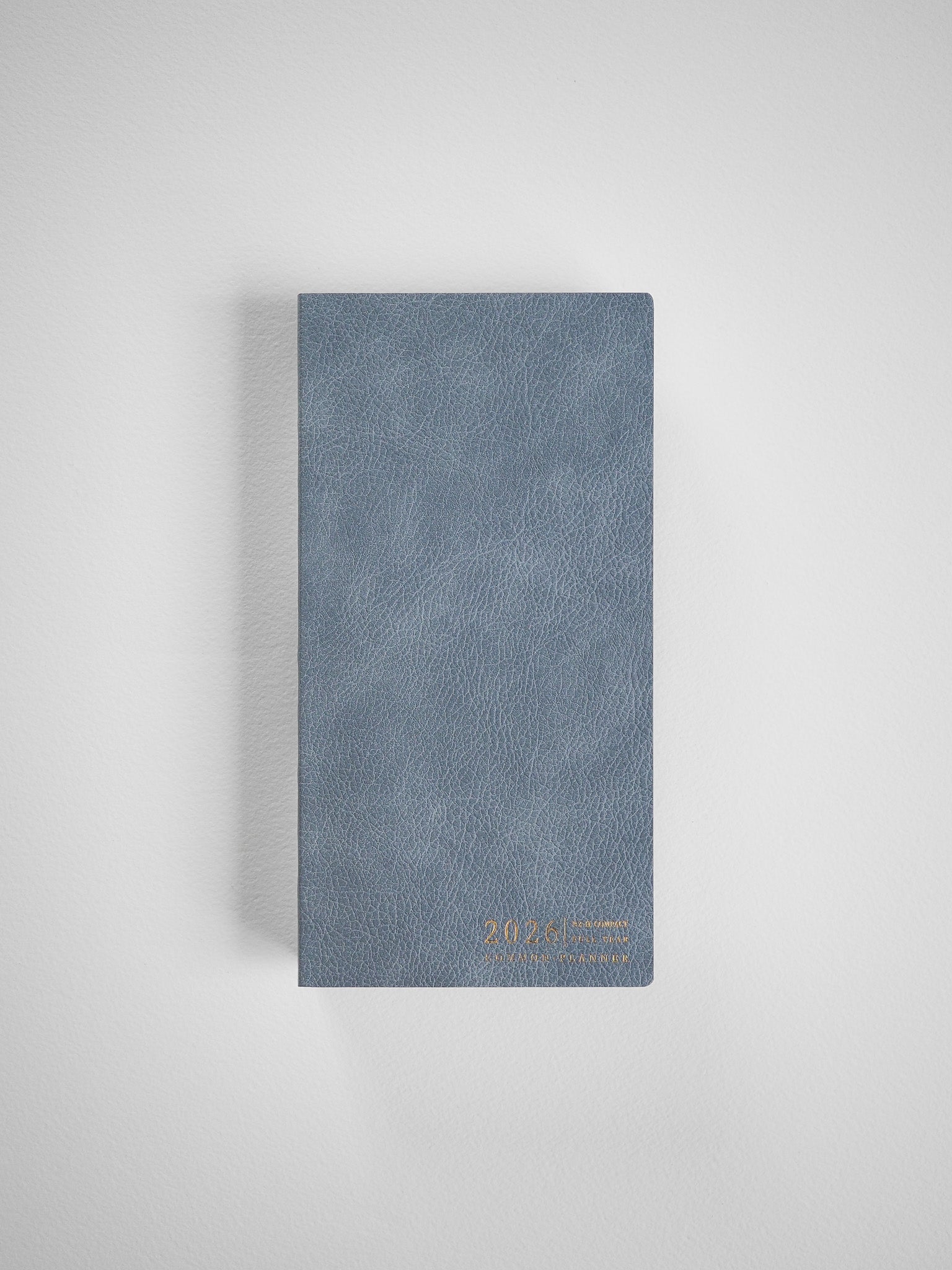 Compact slate blue planner with a textured faux leather cover and subtle gold-toned 2026 lettering for yearly planning.