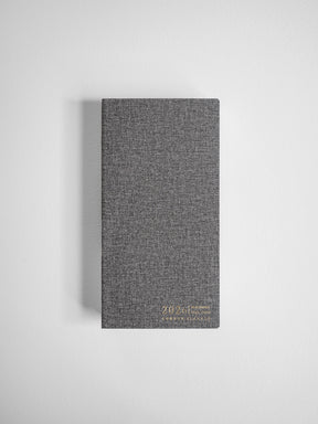 Charcoal gray compact planner featuring a finely woven textured cover and subtle printed 2026 planning details.