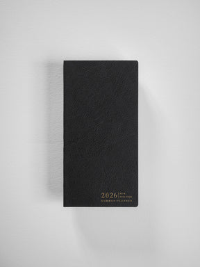A sophisticated black, textured faux leather planner cover featuring centered debossed lettering that reads "2026 Common Planner" for organization.