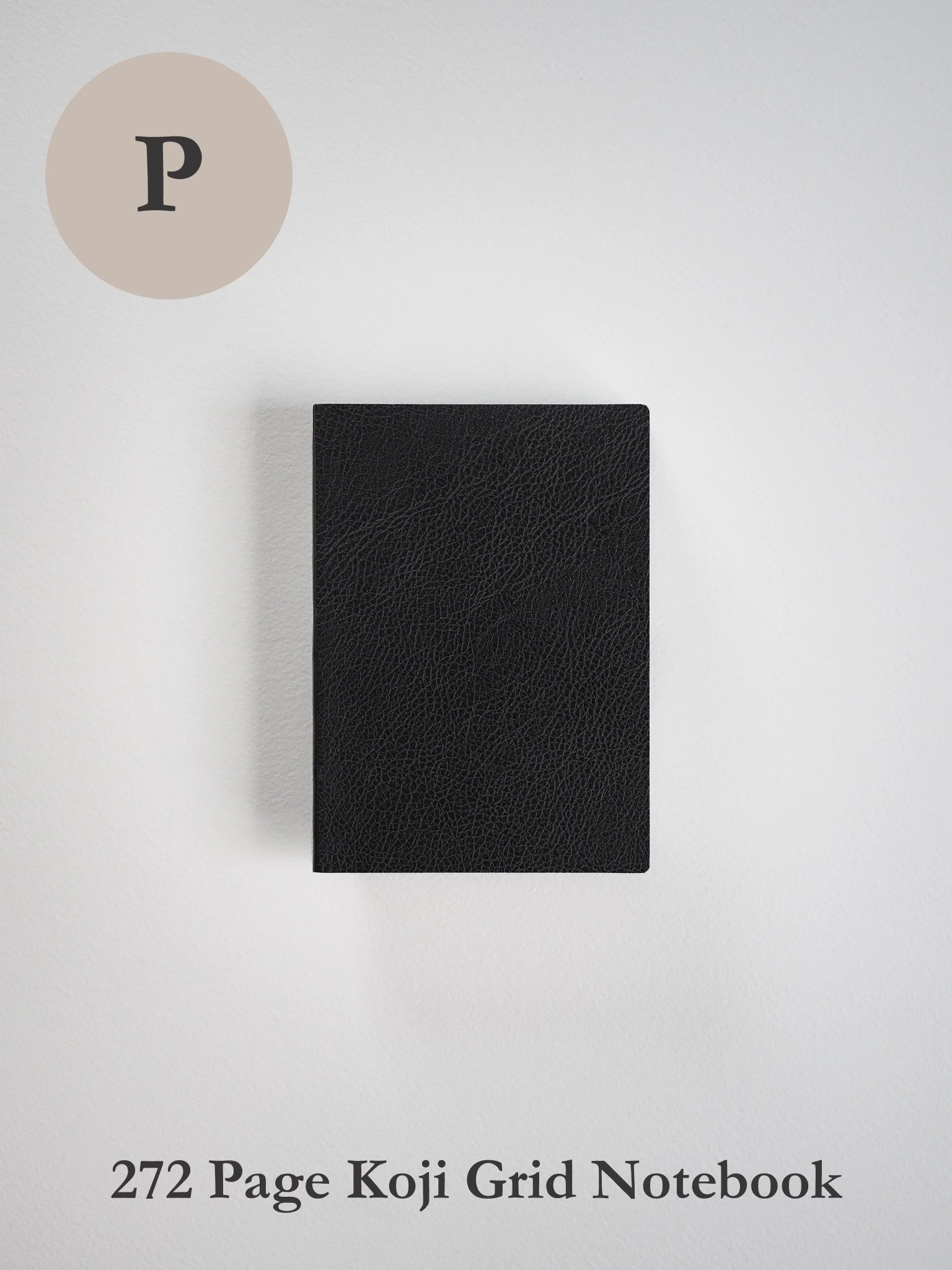 A black textured notebook with a grid layout and 272 pages, shown closed on a light gray background. A beige circle containing the letter 'P' is in the top-left corner, and the text '272 Page Koji Grid Notebook' is at the bottom.
#Color_Onyx