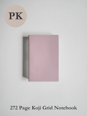 A dusty pink notebook with a grid layout, shown closed on a light gray background. Text at the bottom reads '272 Page Koji Grid Notebook' and a beige circle at the top left reads 'PK'.
#Color_Fairyfloss