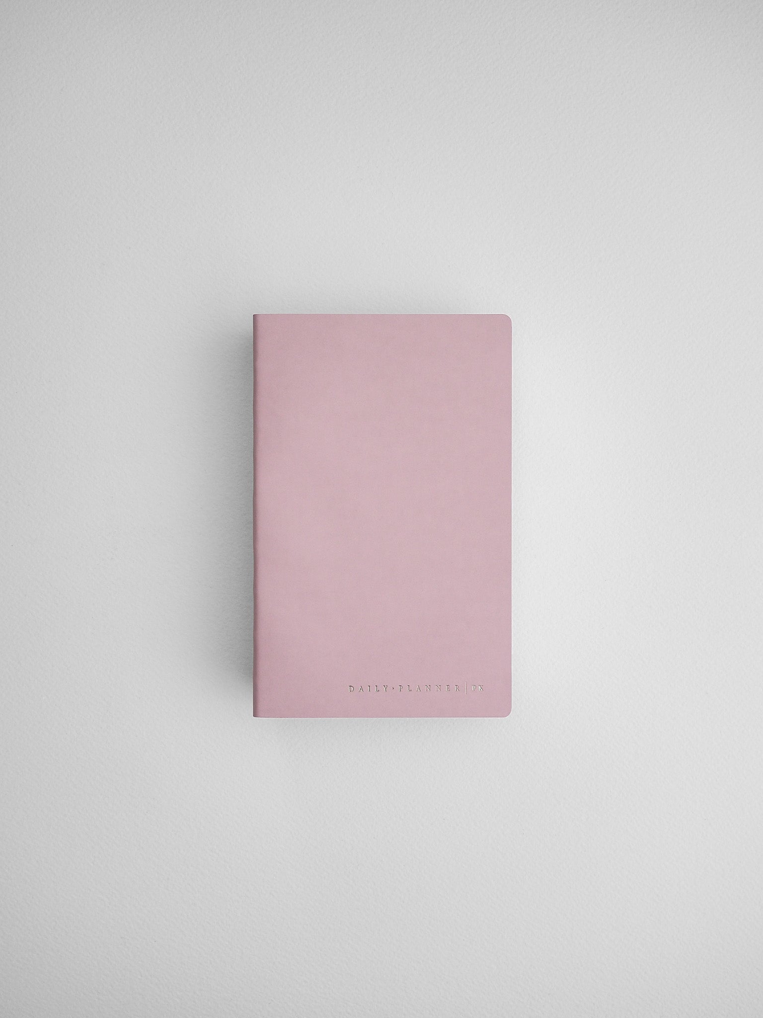 Simple dusty rose daily planner notebook with minimal black branding, designed for organization and journaling.