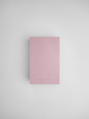 Minimalist blush pink daily planner notebook featuring black lettering and a clean, modern design for journaling or scheduling.