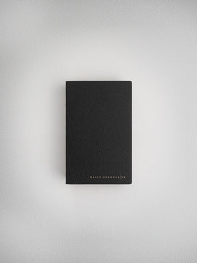 Minimalist black faux-leather daily planner notebook, pocket-sized and debossed with the brand text "DAILY PLANNER | PK," ready for daily organization.