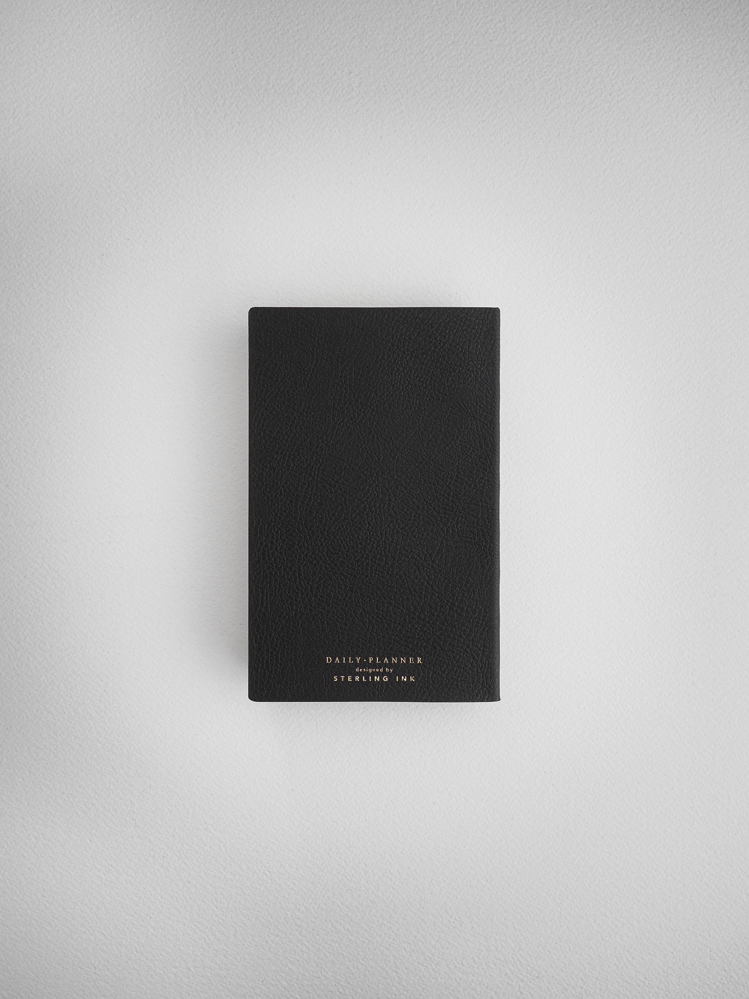 Matte black daily planner notebook with centered white typography branding that reads "Daily Planner" and "Steeling Ink."