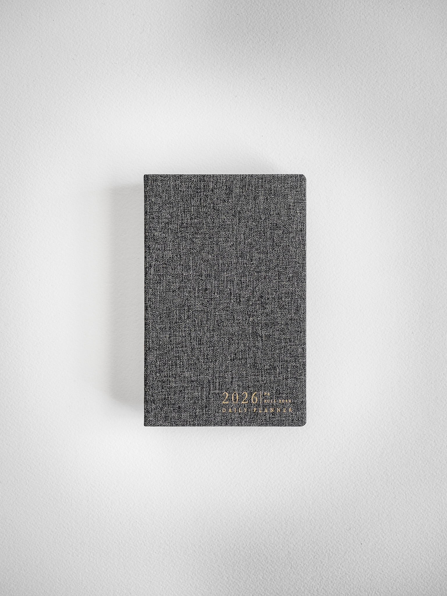 Dark gray, textured pocket daily planner cover printed with "2026" and "Daily Planner" in light lettering, ready for year-long scheduling.