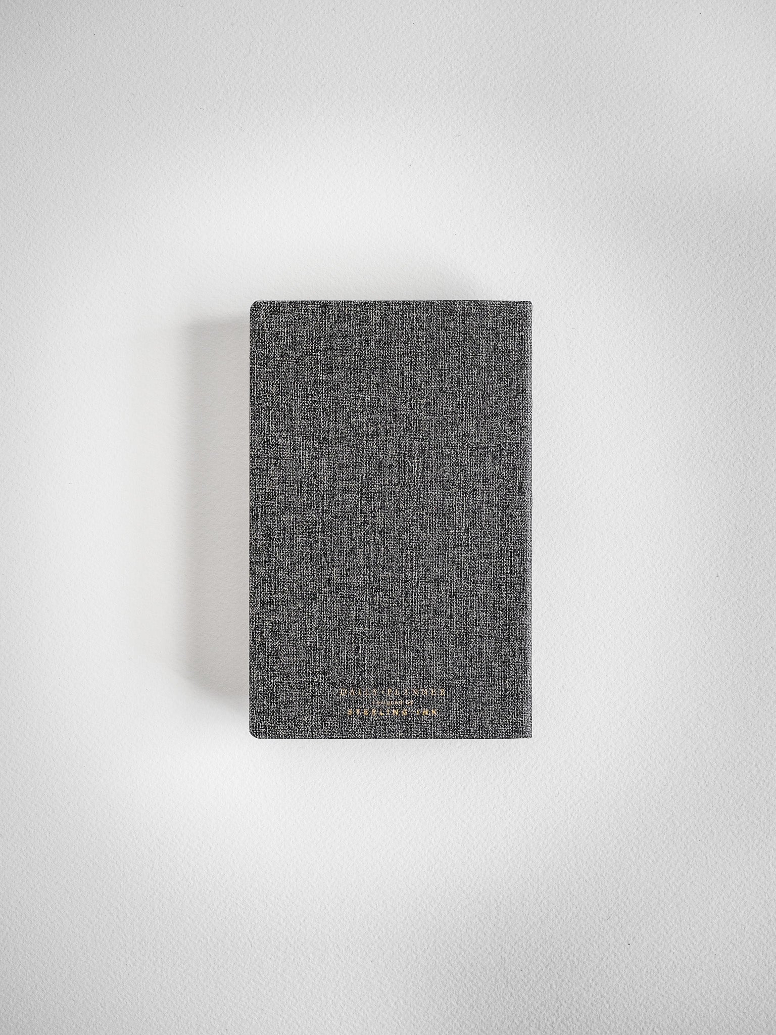 Dark gray, speckled fabric pocket daily planner for 2026, featuring a subtly textured cover design for organized planning.
