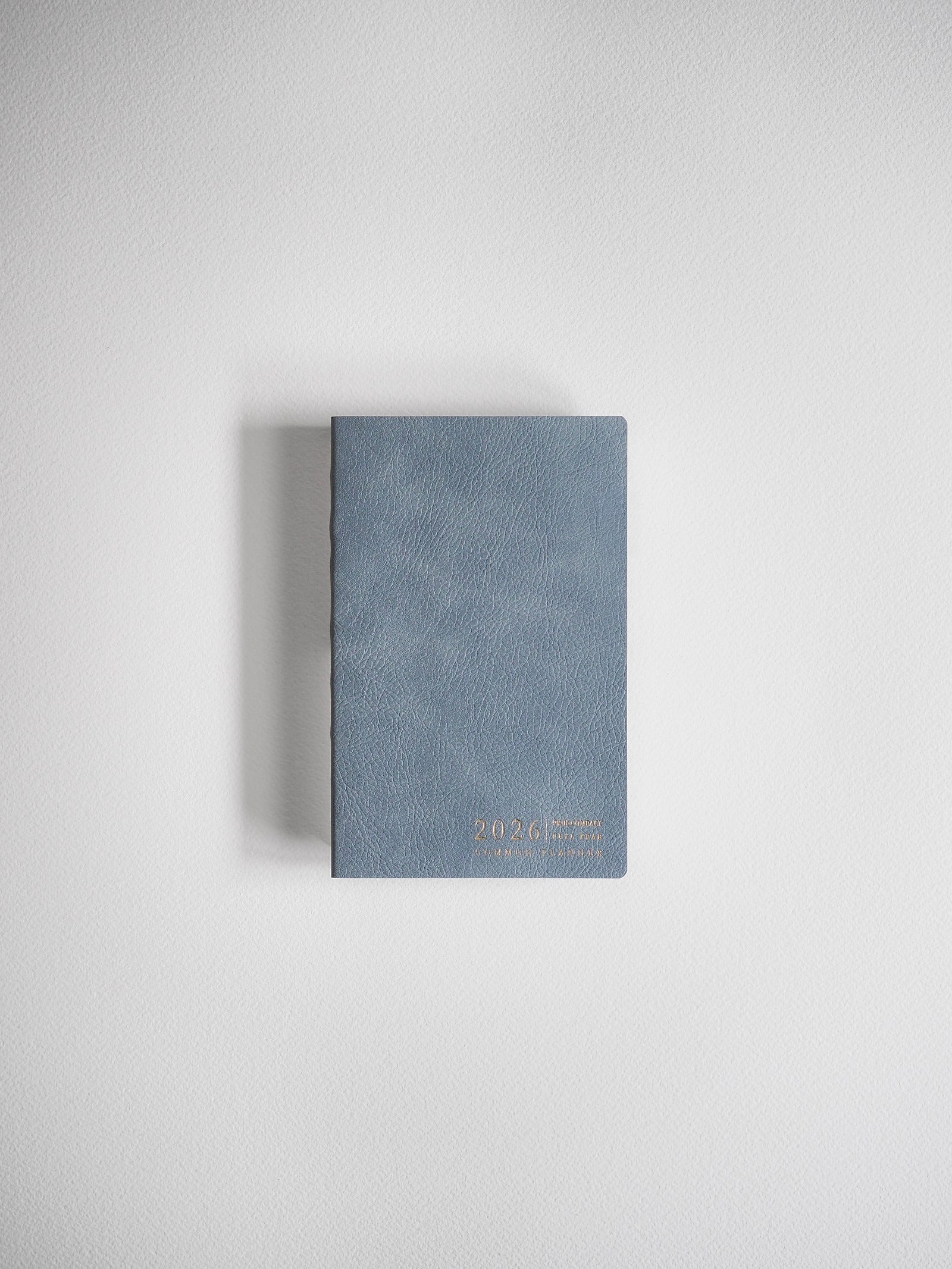 Compact, matte slate-gray journal with a horizontal orientation and elegant gold foil typography displaying the year 2026.