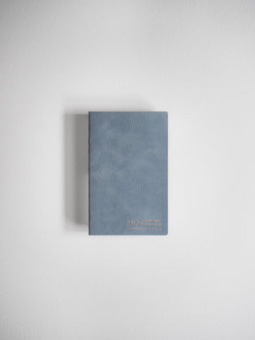 Compact, matte slate-gray journal with a horizontal orientation and elegant gold foil typography displaying the year 2026.