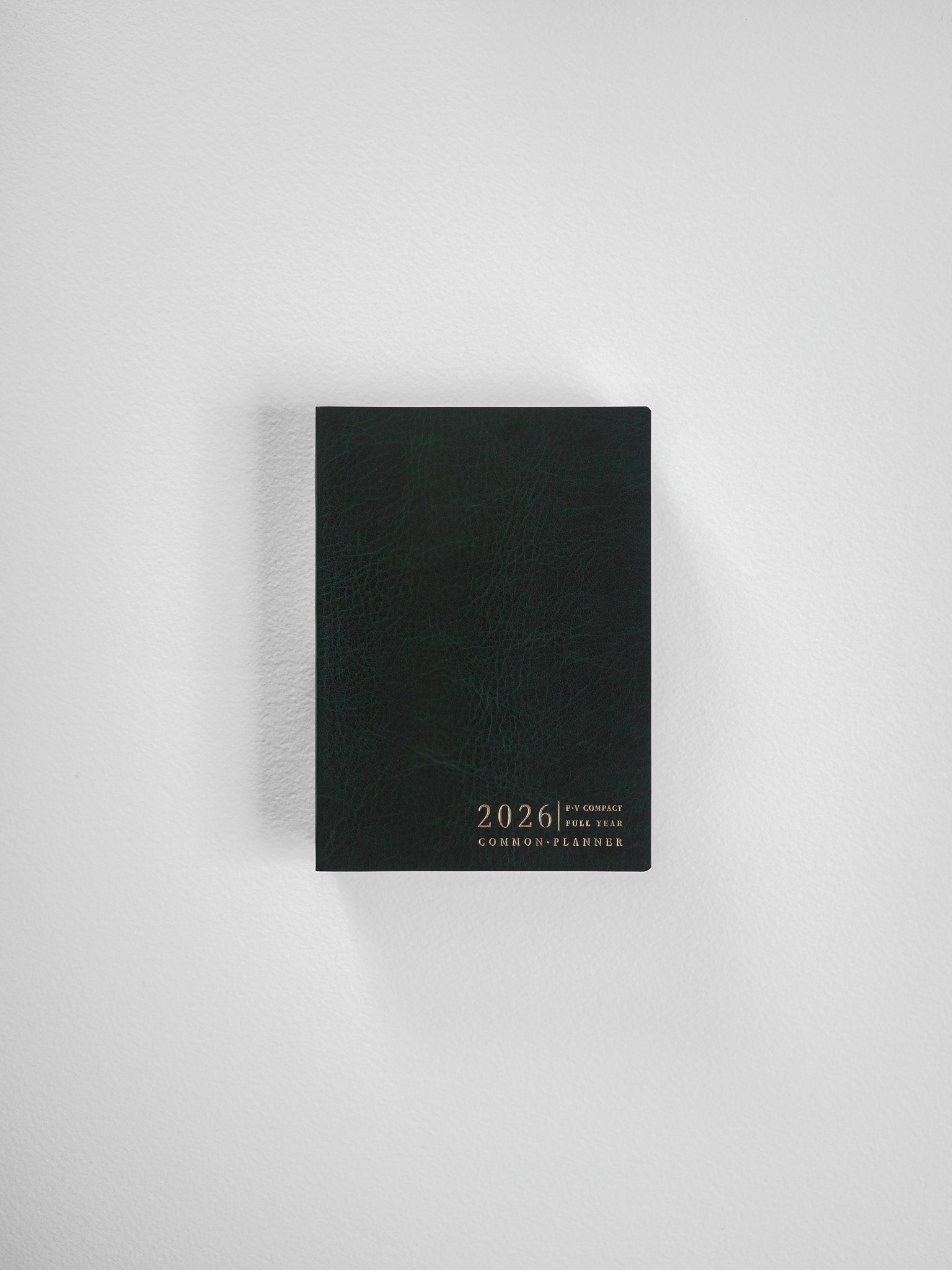 Vertical black planner with a textured cover, featuring elegant gold embossing of "2026" and "Common Planner," ideal for yearly organization.
