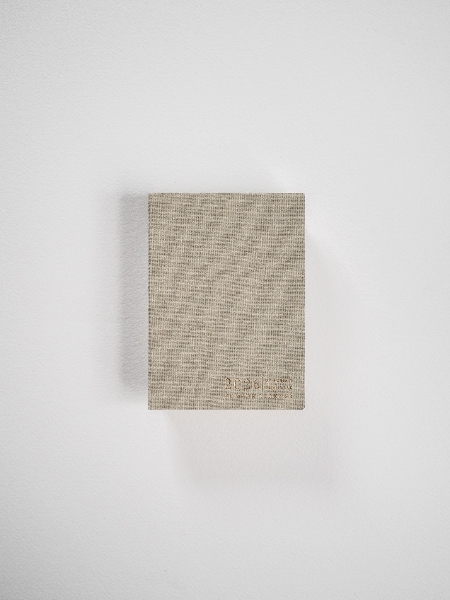 Compact vertical planner with a natural beige cover, featuring minimalist typography displaying the years "2026" and "Common Planner."