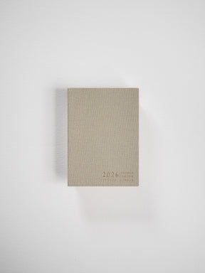 Compact vertical planner with a natural beige cover, featuring minimalist typography displaying the years "2026" and "Common Planner."