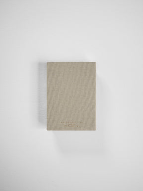 Compact, vertical planner in a natural beige linen texture, featuring minimalist, debossed branding suitable for comprehensive 2026 year organization.