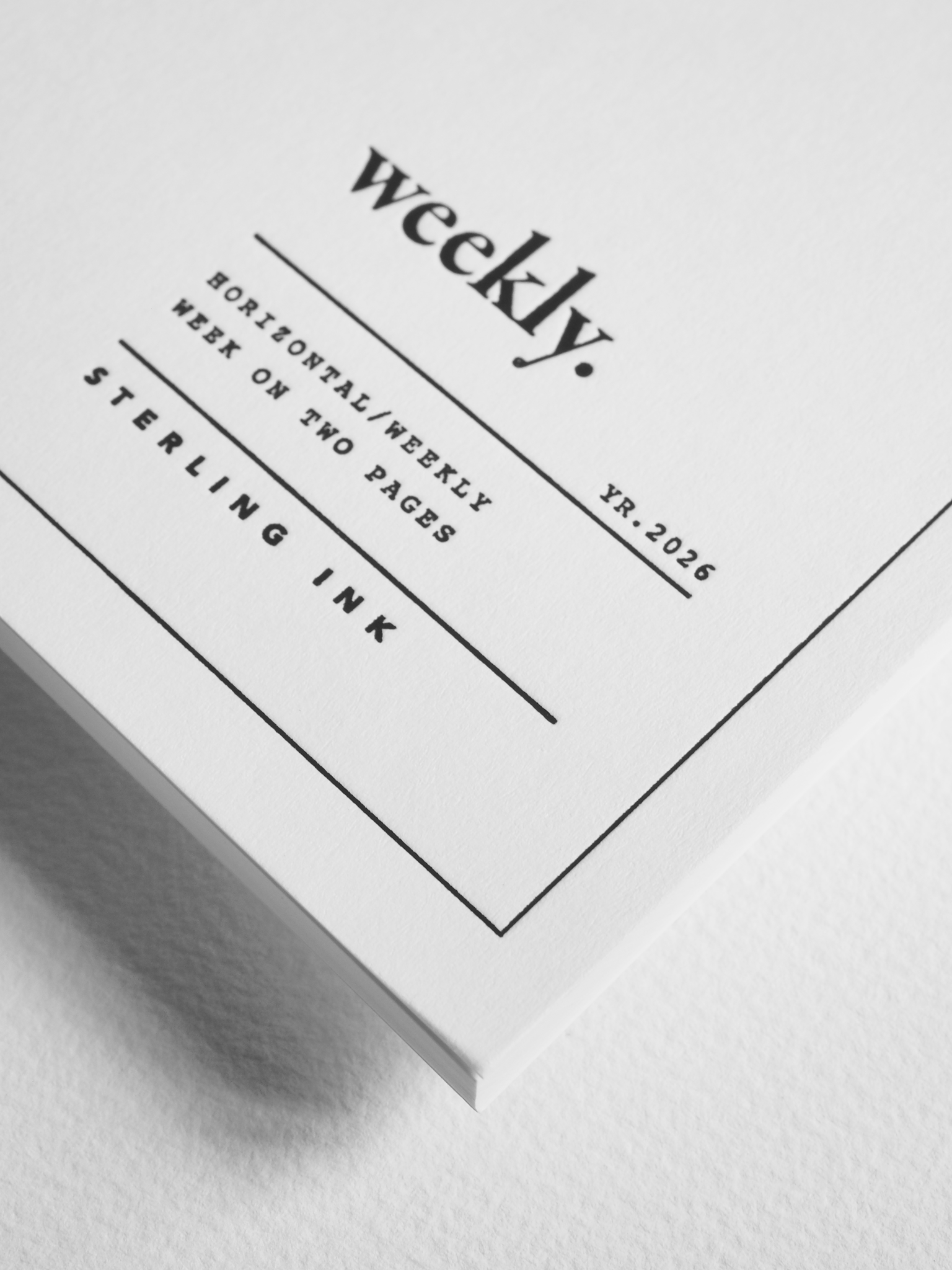 Minimalist white dated planner insert displaying "weekly." and "STERLING INK" in bold black typography, featuring horizontal weekly layouts for 2026 planning.