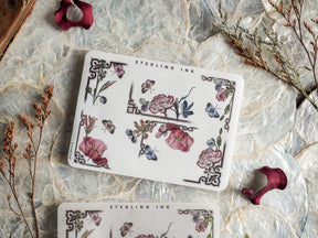 Detailed sticker sheet featuring vintage botanical artwork with blooming flowers, delicate blue butterflies, and elegant black framing borders.