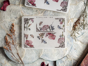 Vintage decorative sticker sheets featuring a delicate botanical pattern of blush roses, deep red florals, blue butterflies, and intricate corner borders.