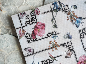 Detailed vintage botanical sheet featuring pink peonies, blue butterflies, and elegant floral motifs printed on graph paper.