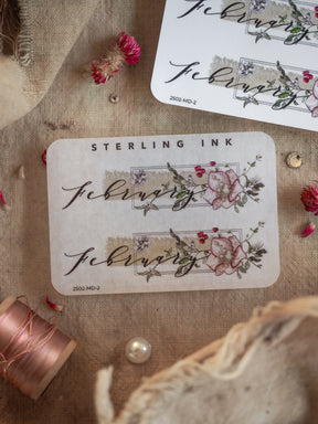 Elegant vintage sticker featuring "February" in script, framed by a delicate wreath of blush roses and green foliage.