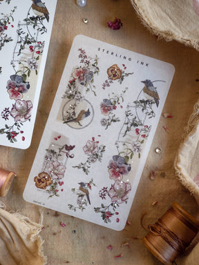 Elegant botanical sticker sheet featuring detailed silver foil illustrations of vintage flowers, delicate foliage, and small woodland birds.