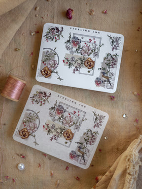 Delicate sheets of vintage floral stickers featuring rose clusters, decorative corners, and intricate border designs with subtle silver foil accents, titled "Sterling Ink."