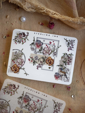 Botanical sticker sheet featuring muted jewel-toned florals, leafy accents, and decorative corner borders, highlighted with delicate silver foil detailing.