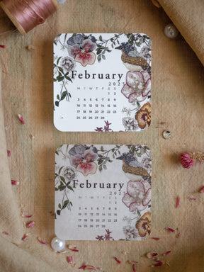 Elegant February 2025 monthly calendar piece framed by romantic watercolor florals, featuring roses and delicate greenery in muted blush and gray tones.