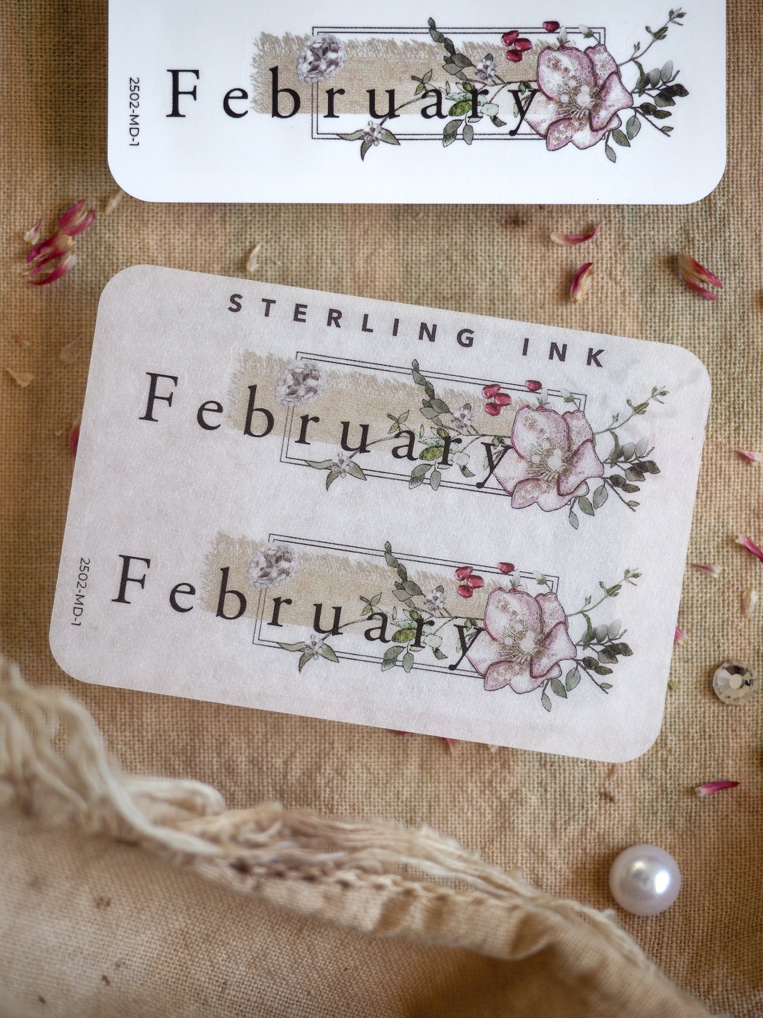 Vintage-themed stickers declaring "February," adorned with realistic watercolor illustrations of dusty pink and mauve blossoms and delicate foliage.