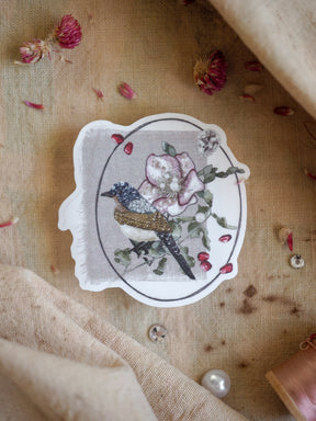 Detailed vinyl sticker featuring a botanical illustration of a small songbird perched next to soft pink watercolor flowers.