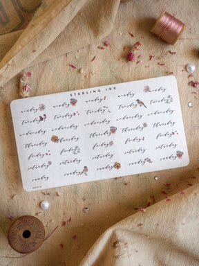 Printable weekly sticker sheet featuring the days of the week—Monday through Sunday—printed in elegant reddish-brown lettering on cream cardstock.
