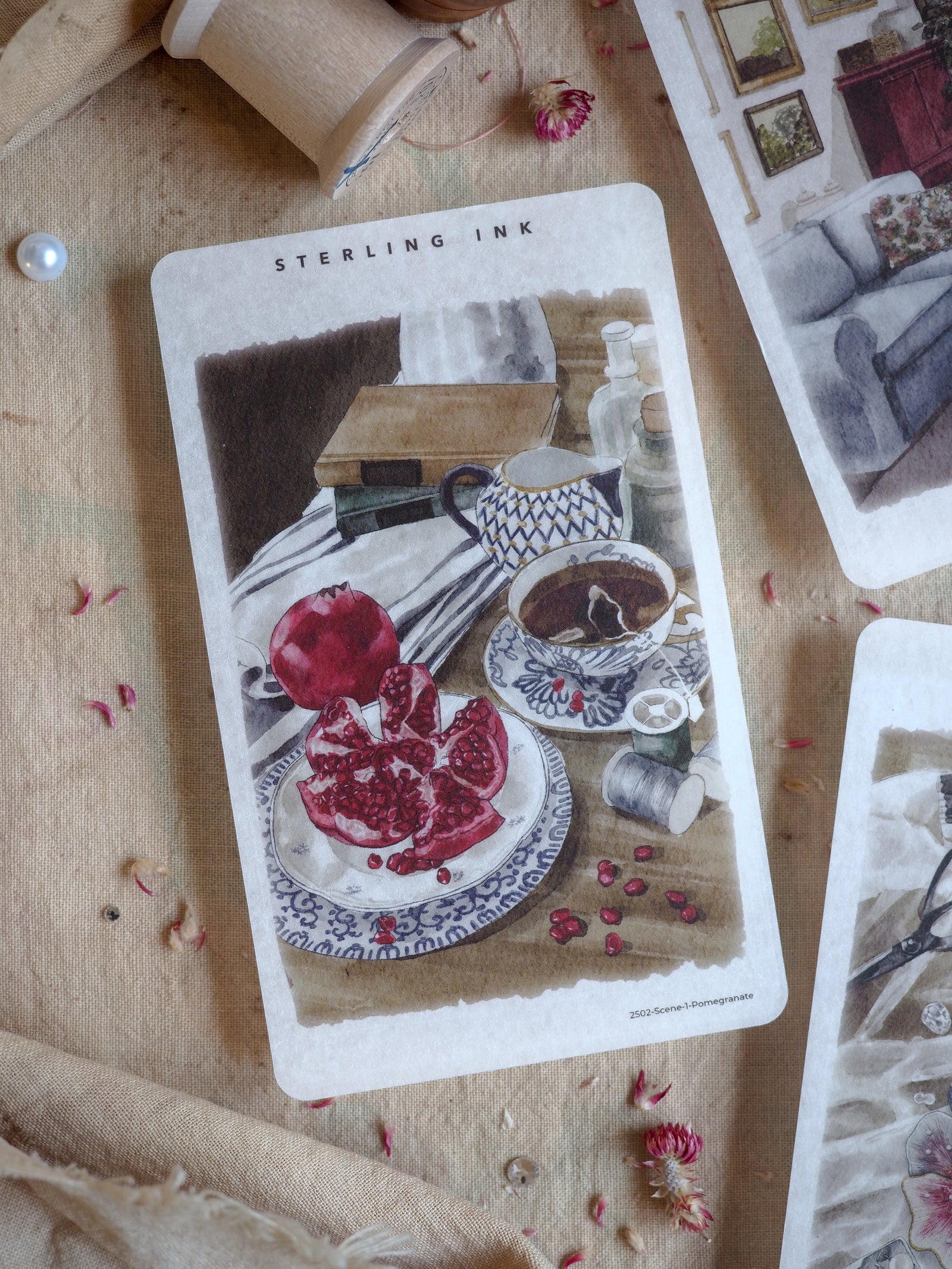 Vintage illustration sticker depicting a still life arrangement of sliced pomegranates, a teacup, and natural elements on a rustic wooden surface.