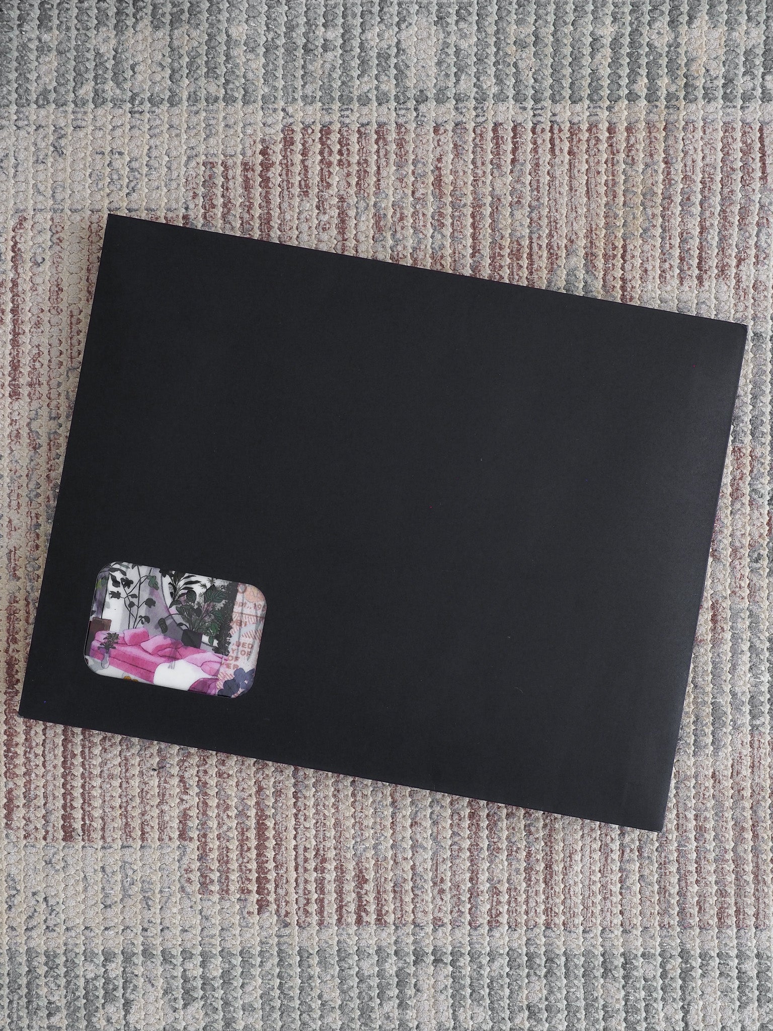 Sleek, matte black subscription journal featuring a corner accent sticker with a blend of dark florals and soft pink spring patterns.