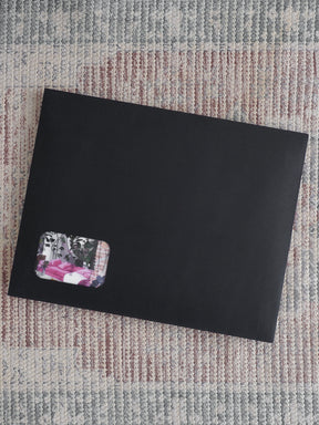 Sleek, matte black subscription journal featuring a corner accent sticker with a blend of dark florals and soft pink spring patterns.